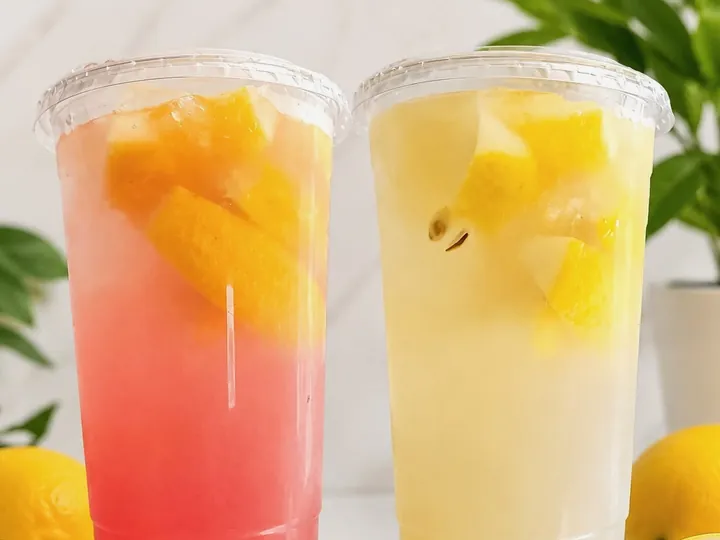 Strawberry and classic lemonade in clear cups, topped with fresh lemon wedges.